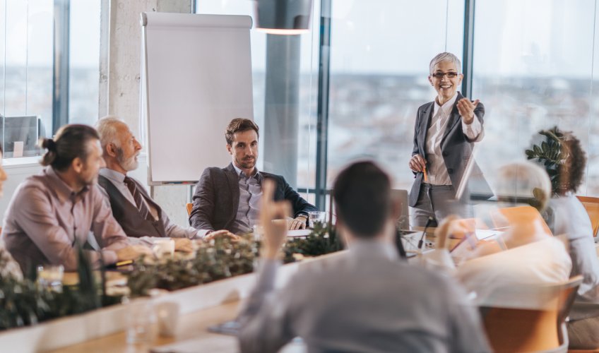 Happy senior manager talking to her colleagues on a business meeting in a board room Happy senior manager talking to her colleagues on a business meeting in a board room